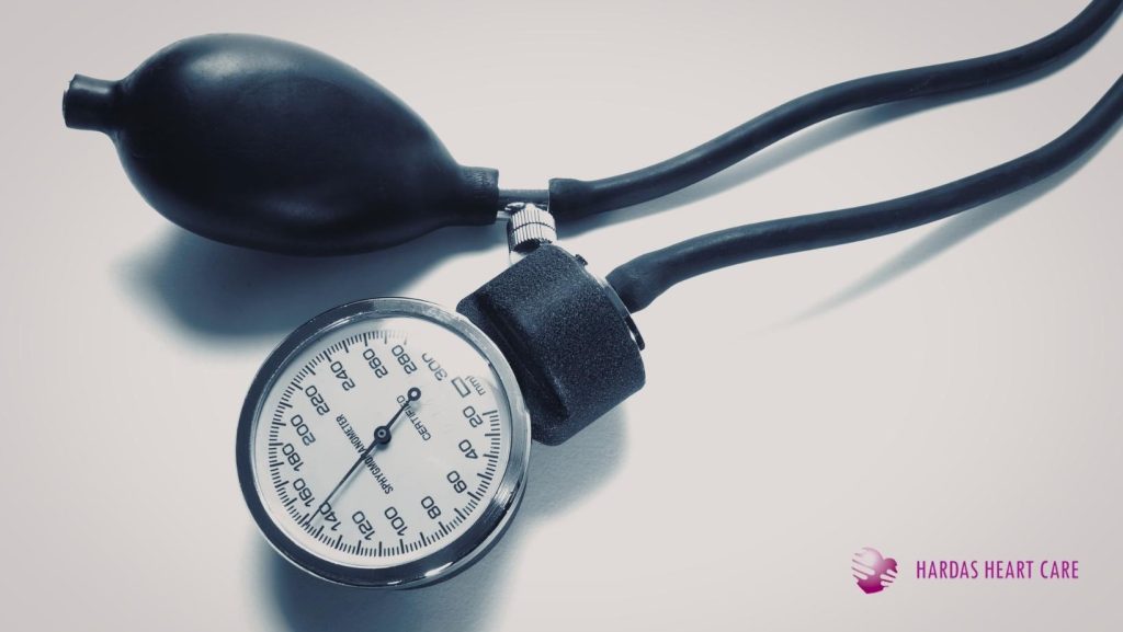 A healthcare professional measuring a patient's blood pressure with a digital monitor in a clinic setting. Best hypertension clinic in Pune